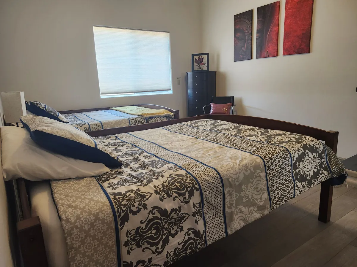The Healing Room: a full bed with a patterned quilt under a window, with art on the wall