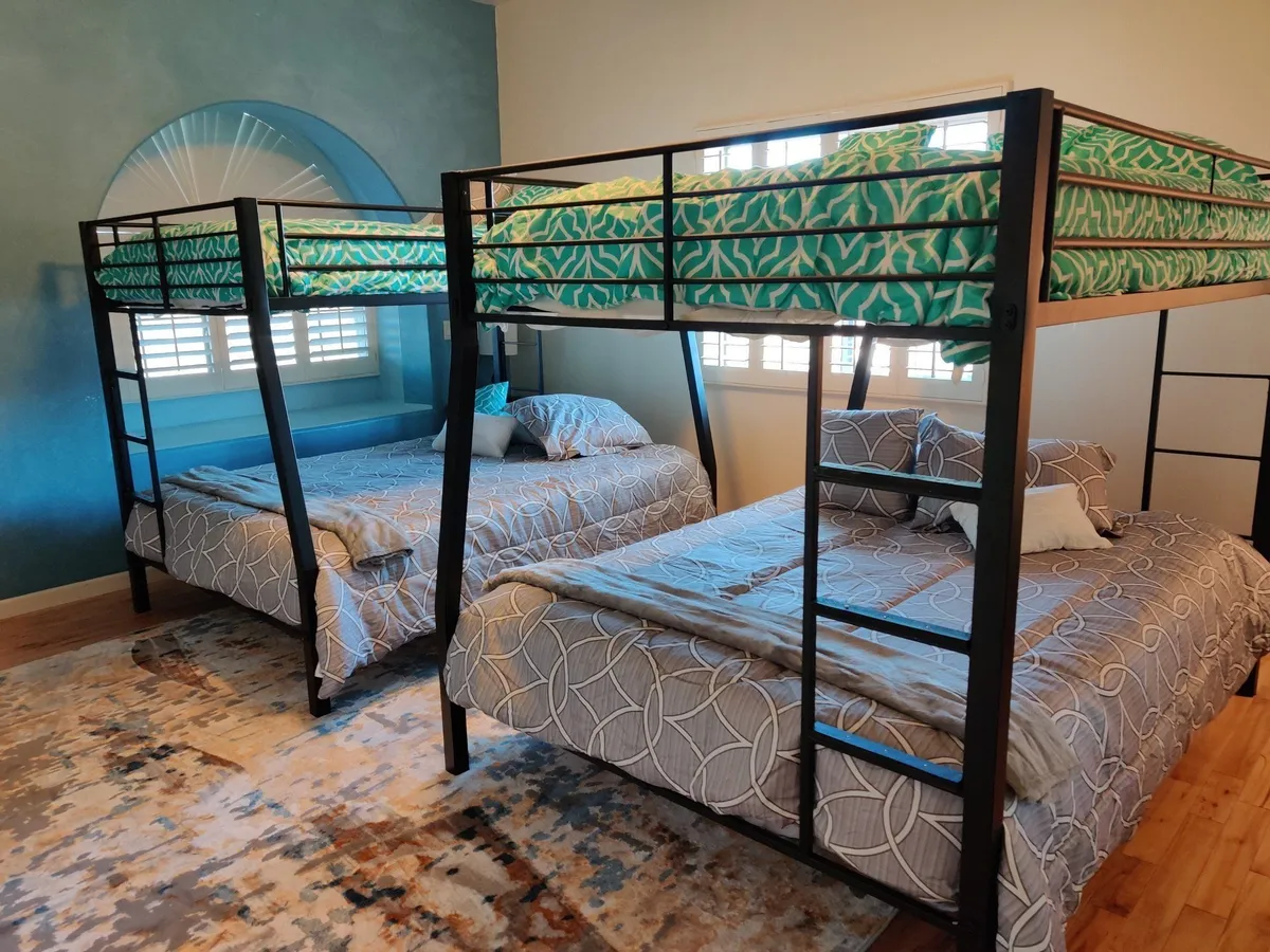 The Peace Room: two metal bunk beds with green and grey bedding under an arched window